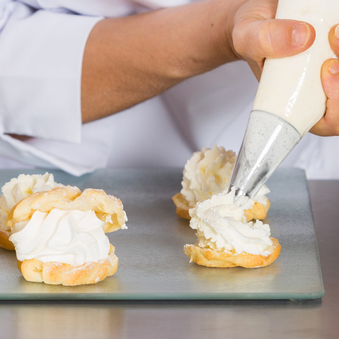 Baker piping cream on cakes - Dairy and Ice cream - AAK