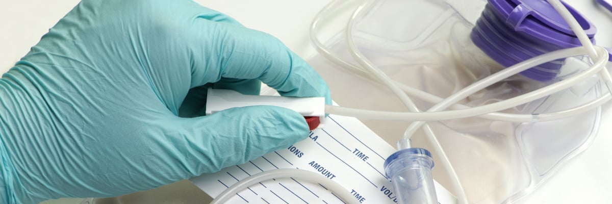 Hand in surgeon glove holding IV - Special Nutrition - AAK