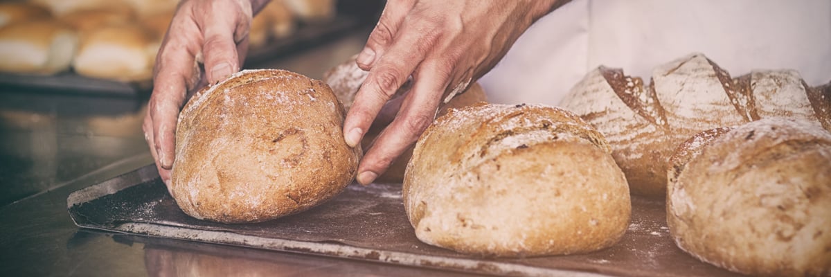 Baker Takes out Loafs of Bread From an Oven - Bakery - AAK