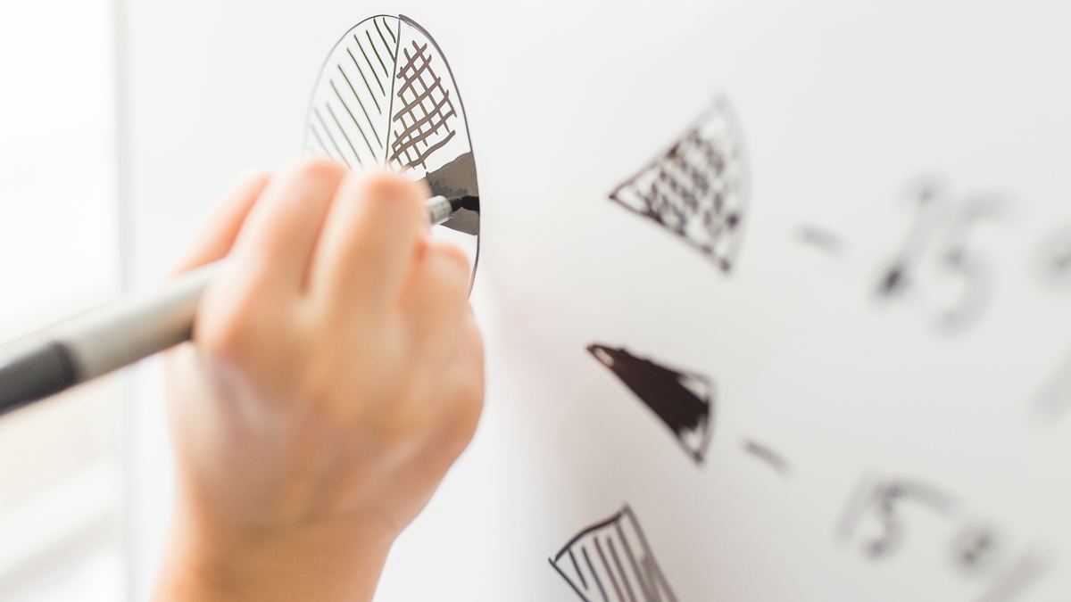 Close-up of a hand holding a pen and writing on the whiteboard - Investors - AAK