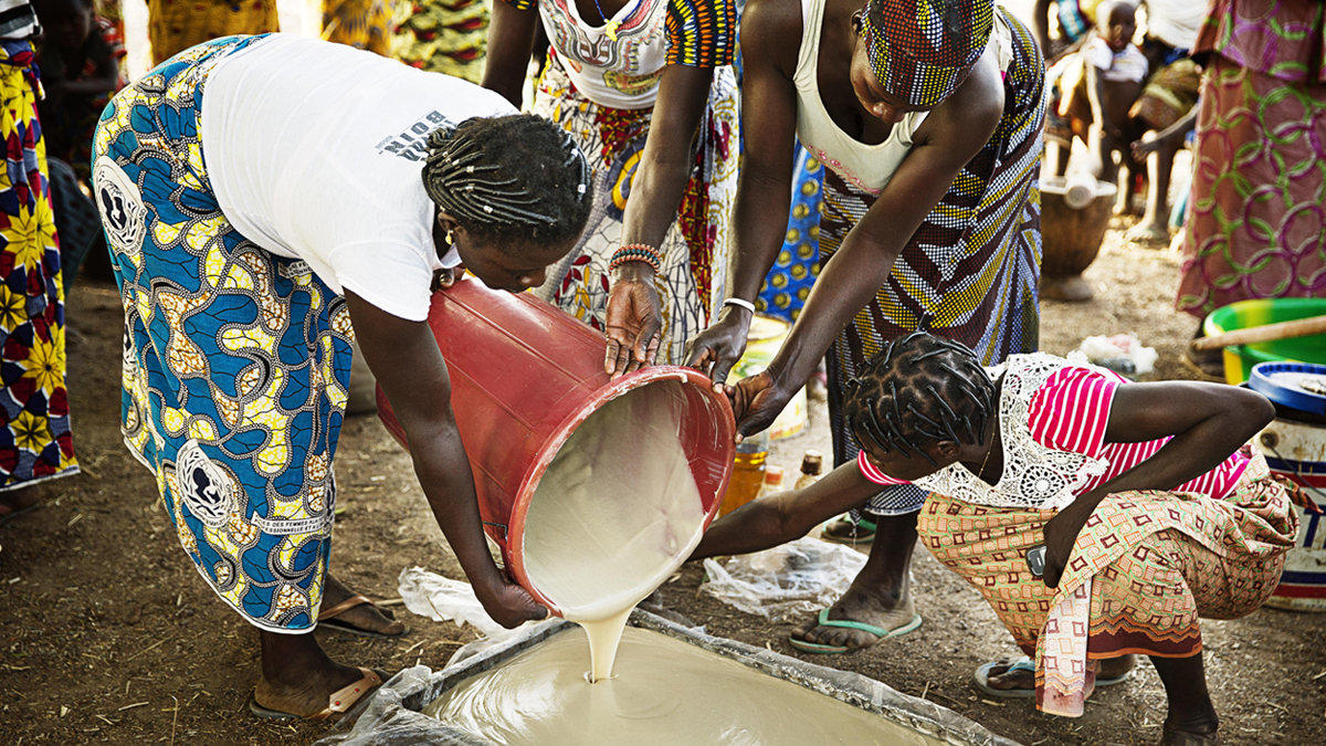 Women in Burkina Faso pouring shea kernels into a pot - Personal Care - AAK